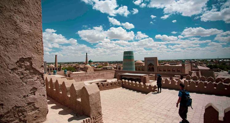 Vue panoramique depuis le toit sur l'horizon de briques de terre cuite de Khiva avec l'iconique minaret Kalta Minor sous un ciel vibrant.