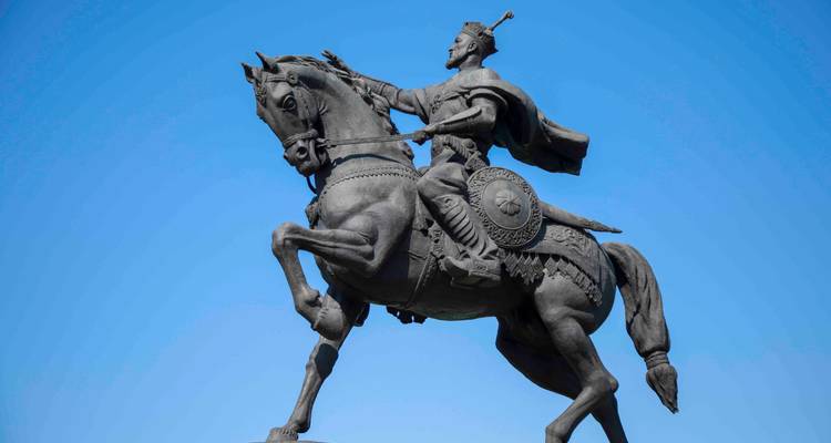 Profil d'une statue ornée de cavalier s'élançant vers l'avant contre un ciel bleu.