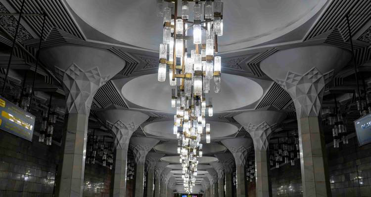Hall de station de métro ornementé de l'époque soviétique avec des lustres spectaculaires et des plafonds géométriques.