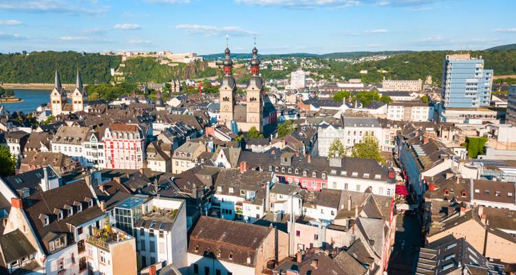 Weitläufige Luftaufnahme der Koblenzer Altstadt mit Kirchtürmen, dem Zusammenfluss von Rhein und Mosel und einer Bergfestung.