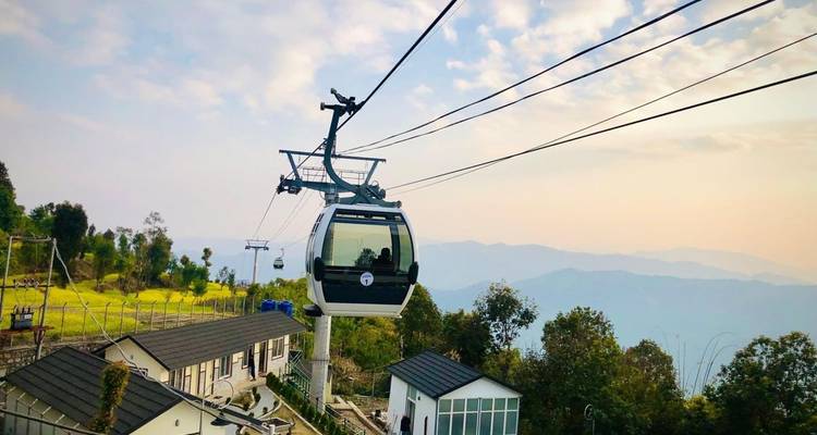 El teleférico moderno se desliza sobre un complejo turístico en la ladera hacia cadenas montañosas brumosas al atardecer
