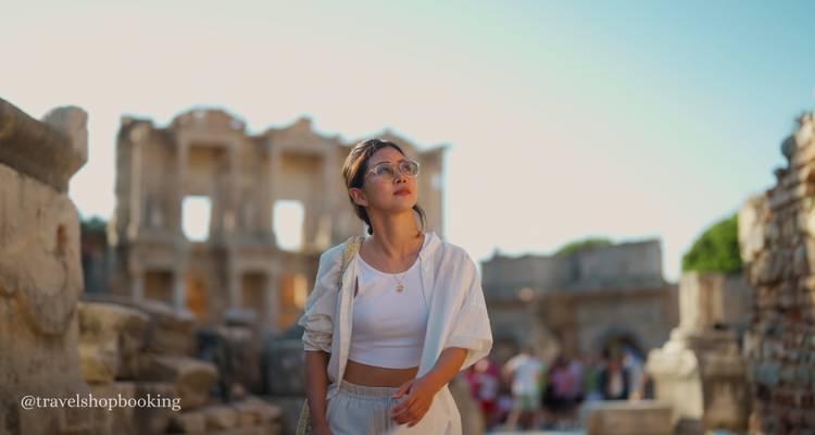 Voyageur élégant en tenue blanche se promenant parmi les ruines de la bibliothèque de Celse à Éphèse ; texte de filigrane dans le coin.