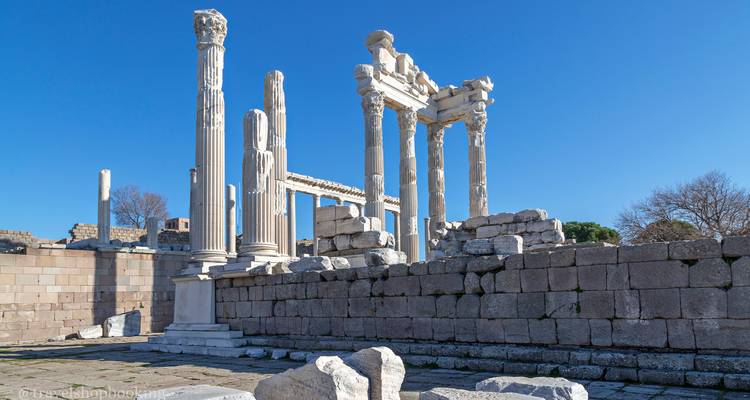 Colonnes de marbre blanc bien conservées du Temple de Trajan à Pergame contre un ciel bleu dégagé, filigrane dans le coin.