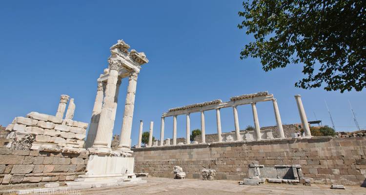Plan large de la colonnade survivante et des murs de pierre de Pergame sous un ciel dégagé, filigrane inclus.