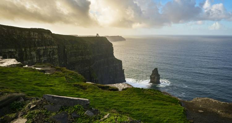 Iconic Cliffs of Moher sweeping into the Atlantic with golden light illuminating sea spray.