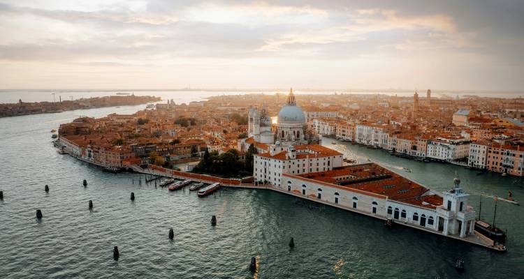 Sweeping aerial view of Venice with Santa Maria della Salute and terracotta rooftops at dusk.
