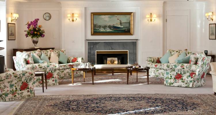 Elegante lounge met bloemige banken, klassieke open haard en groot Oriëntaals tapijt.