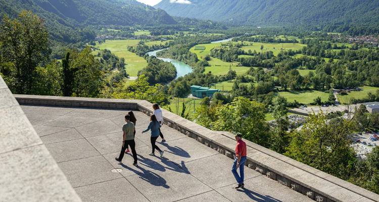 Viajeros caminando por una terraza panorámica con vistas a un exuberante valle fluvial
