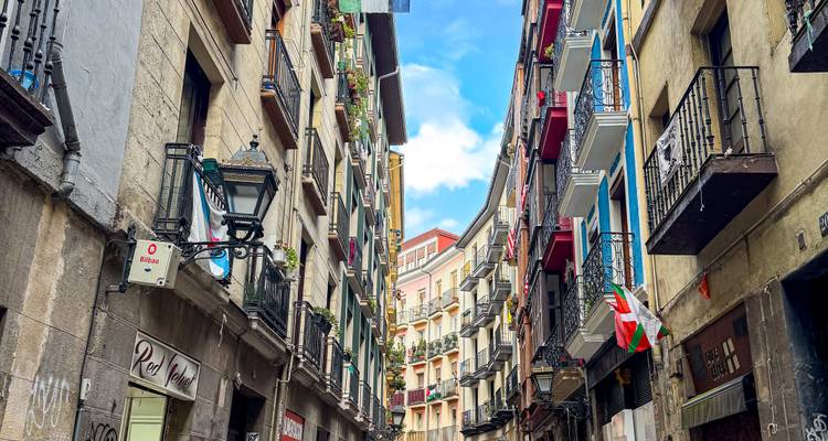 Narrow old street in Bilbao’s historic centre lined with tall buildings and balconies.