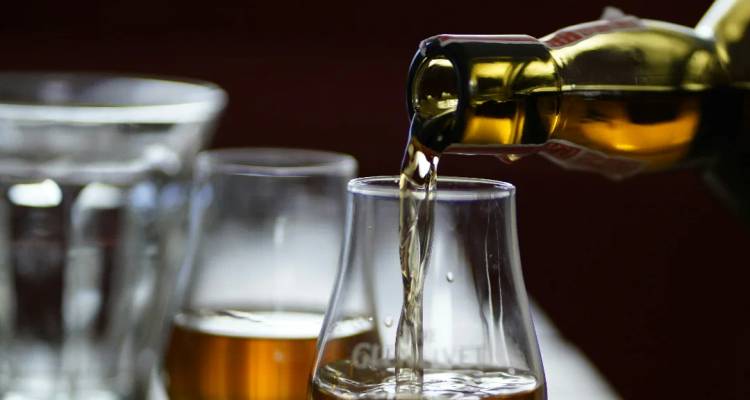 Se vierte whisky dorado en una copa de degustación en un primer plano en un bar.