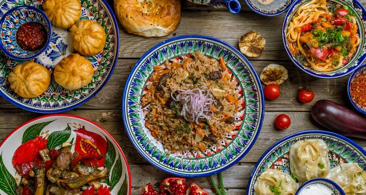 Étalage coloré de plats ouzbeks traditionnels disposés sur des assiettes à motifs sur une table rustique.