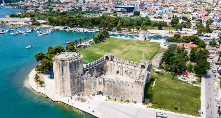 Toma aérea de la Fortaleza de Kamerlengo junto a aguas turquesas y puerto deportivo en Trogir