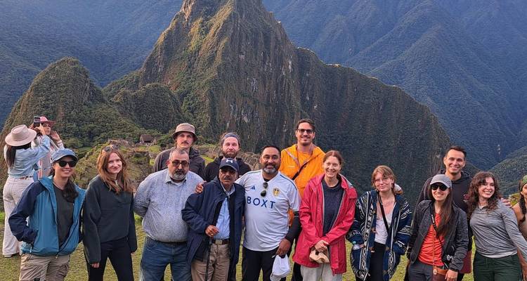 Groupe de touristes posant joyeusement avec la montagne du Machu Picchu en arrière-plan.