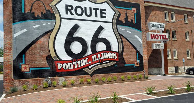 Murale en briques colorée célébrant la Route 66 à Pontiac, Illinois, avec un grand logo en forme de bouclier et un graphique de route.