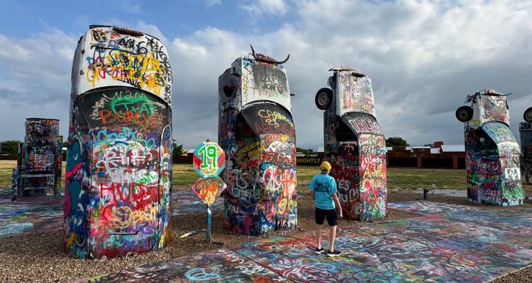 Autos enterrados cubiertos de grafiti en la peculiar instalación artística Cadillac Ranch bajo un cielo dramático.