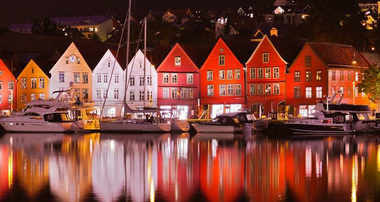 Vista nocturna de las coloridas casas de madera de Bryggen reflejadas perfectamente en las tranquilas aguas del puerto