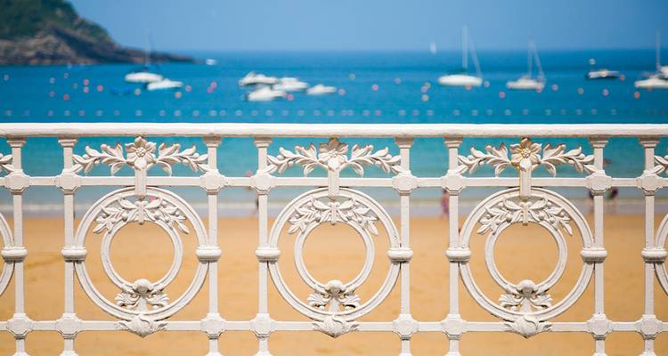 Balustrade blanche décorative de la promenade de San Sebastian avec plage et bateaux flous en arrière-plan