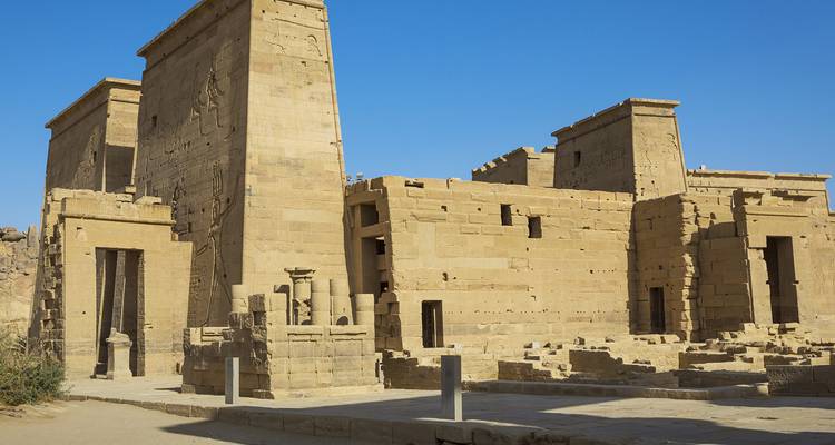 Antiguas estructuras de arenisca y columnas del complejo del Templo de Filae contra un cielo azul profundo.