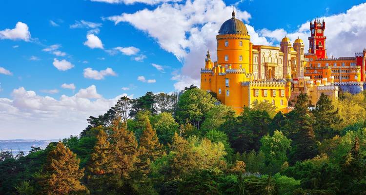 Palacio de la Pena de colores brillantes posado en la cima de una colina boscosa contra un cielo azul vívido.