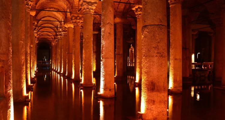 Interior atmosférico de la Cisterna Basílica de Estambul iluminado con reflejos cálidos en agua quieta