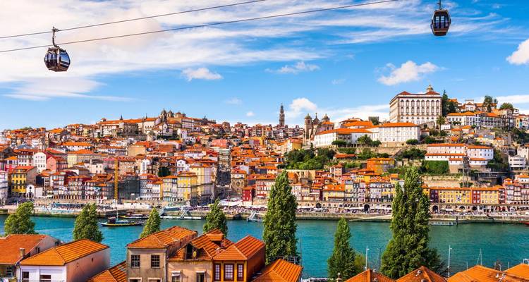 Vista panorámica del horizonte histórico de Oporto a través del Duero con teleféricos deslizándose por encima.
