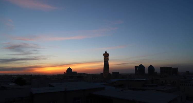 Silhouette de l'horizon de Boukhara avec des minarets à l'aube et des traînées colorées du lever du soleil.