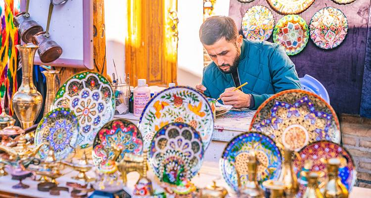 Artisan peignant à la main des assiettes en céramique colorées sur un stand de bazar en plein air.