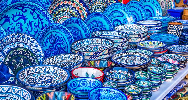 Étalage de bols et assiettes en céramique bleue aux motifs éclatants empilés sur un marché.