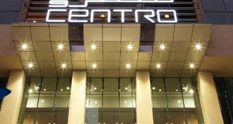 Entrada del hotel con letrero iluminado de 'Centro' y fachada de cristal espejado por la noche.