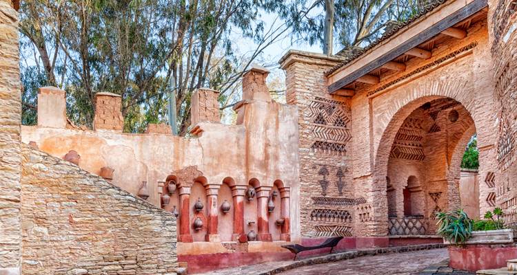 Kleurrijke aardewerk nissen en roodgetinte adobe bogen versieren een rustige binnenplaats in zuidelijk Marokko.