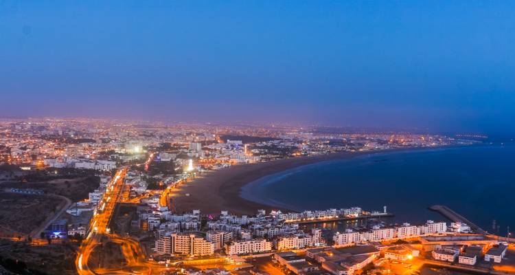 Schemering luchtfoto van de lichten van de stad Agadir die zich om de baai en het lange zandstrand krommen.