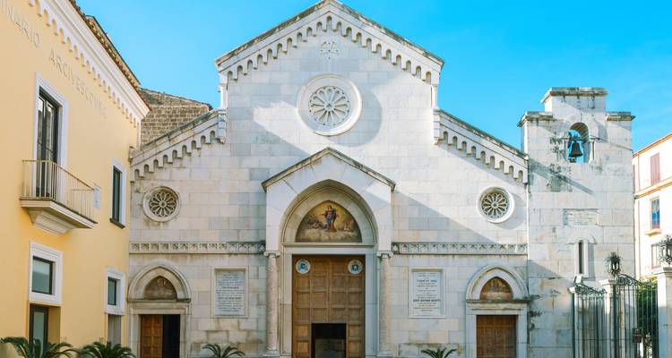 Helder verlichte gevel van een witte stenen kerk in Sorrento tegen een onberispelijke blauwe hemel.
