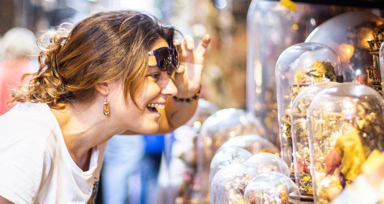 Vrouw onderzoekt enthousiast ingewikkelde beeldjes onder glazen koepels op een ambachtsmarkt
