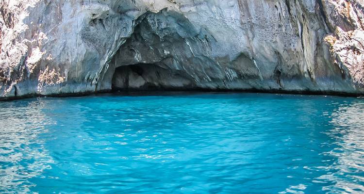 Levendig turkoois zeewater vult een rotsachtige kustgrot met lichtgekleurde kalkstenen wanden