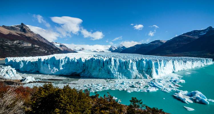 Majestueuze Perito Moreno Gletsjer met torenhoge blauwe ijswand die turquoise wateren ontmoet te midden van met sneeuw bedekte Andes-toppen.