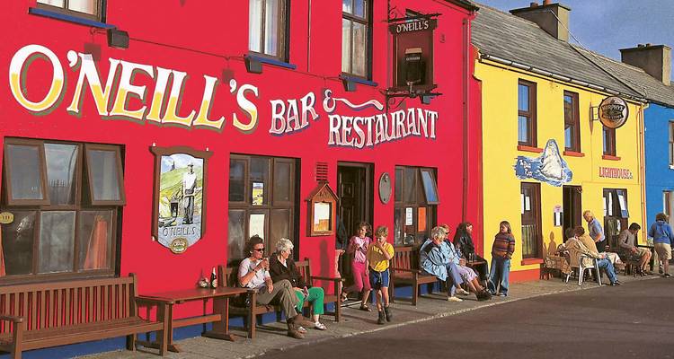 Fachadas coloridas de pub irlandés con lugareños y visitantes sentados y conversando afuera del Bar O'Neill's.