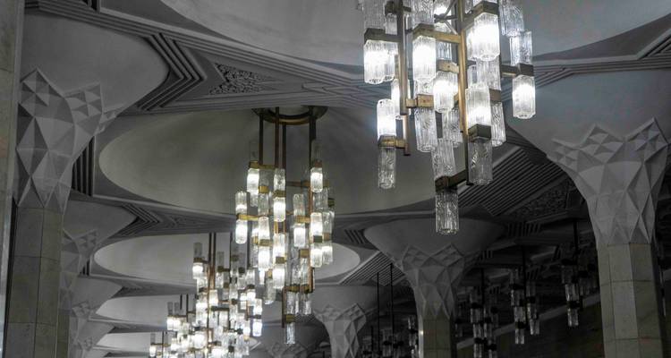 Rangée de lustres en cristal ornementés suspendus à un plafond voûté moderne avec des motifs géométriques