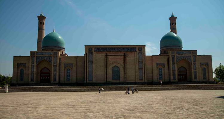 Vue frontale large du complexe de la mosquée Hazrati Imam avec des vélos posés sur la vaste place devant.