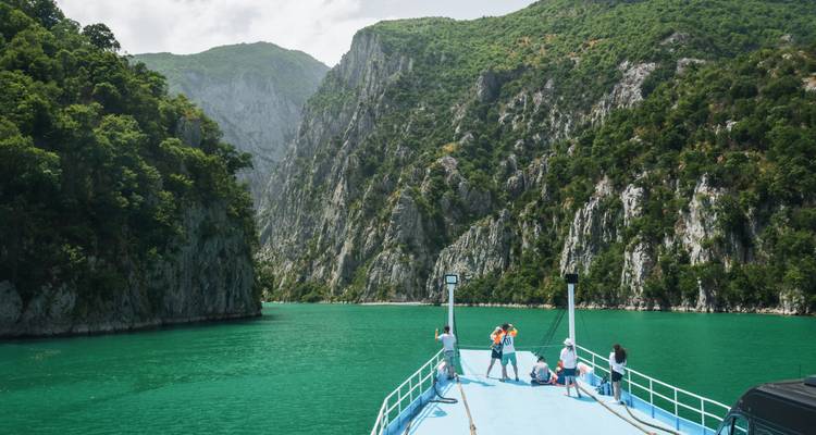 Rondvaartboot die door steile groene kloven vaart op levendig smaragdgroen water