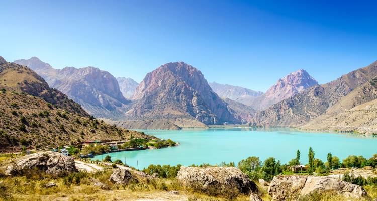 Lago alpino turquesa rodeado de montañas dramáticas y costas rocosas en Tayikistán
