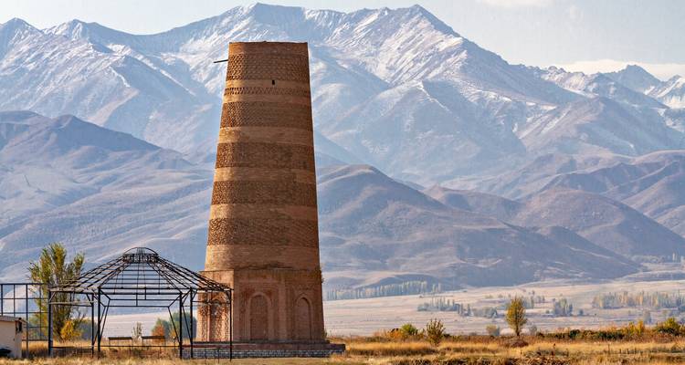 Antigua Torre Burana de ladrillo rojo sobre el telón de fondo nevado de las montañas Tian Shan