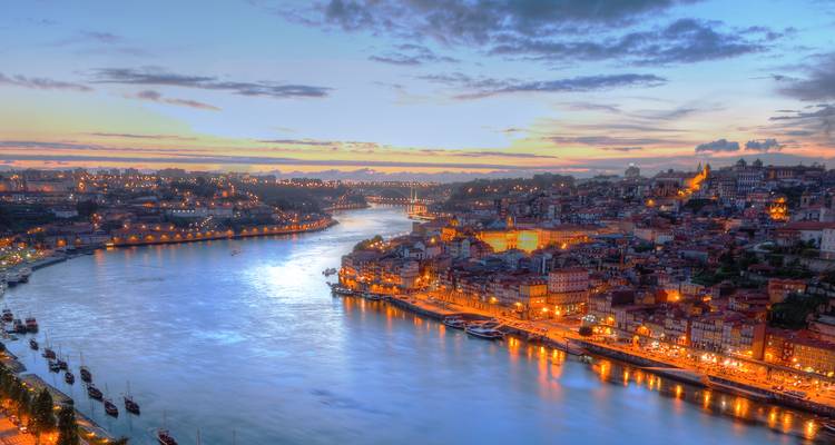 Dämmerlicht-Blick über Porto mit dem Douro-Fluss, der die Stadtlichter und Brücken unter einem farbenfrohen Sonnenuntergangshimmel reflektiert
