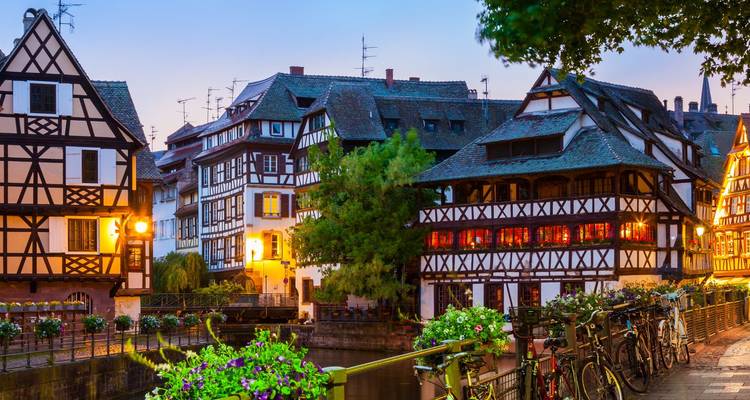 Abendszene des Viertels Petite France in Straßburg mit Fachwerkhäusern, die sich im Kanal spiegeln.