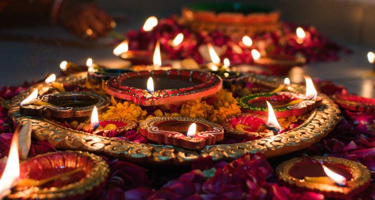 Primer plano de lámparas de aceite de arcilla decorativas dispuestas en un patrón floral con pétalos vibrantes y llamas brillantes