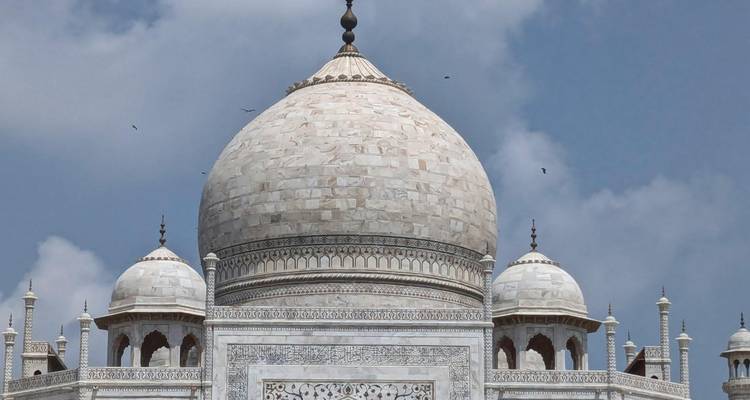 Vista detallada de la cúpula de mármol blanco y los minaretes del Taj Mahal contra un cielo azul