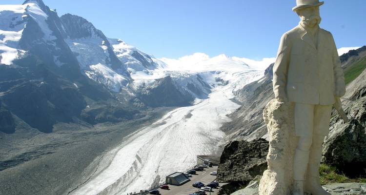Panoramisch gletsjerdal gezien vanaf een bergpas met een standbeeld op de voorgrond