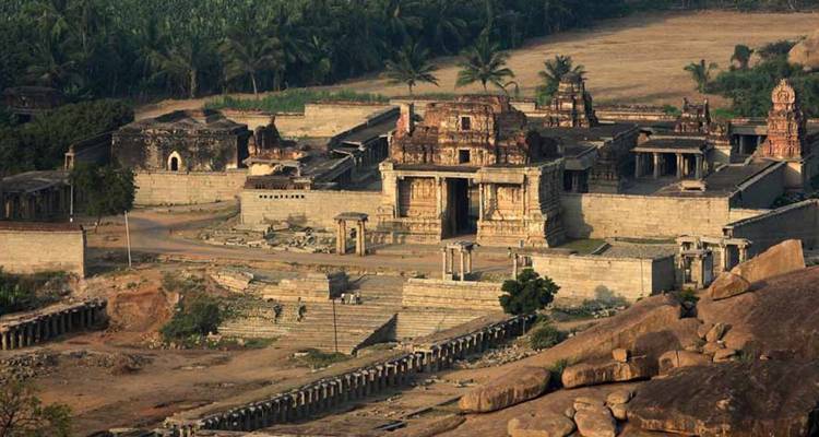 Stenen ruïnes en tempels verspreid tussen rotsachtig landschap bij zonsondergang