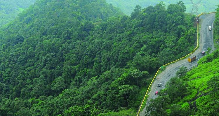 Kronkelende bergweg die door het dichte groene bos van de Western Ghats snijdt