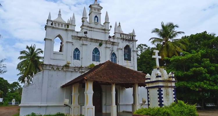 Witte koloniale kerk met puntige torens omgeven door palmbomen
