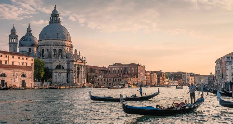 Gondolas drift along Venice's Grand Canal at sunset with Santa Maria della Salute in view.